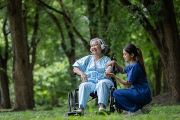 Joyful Elderly Woman in a Wheelchair Enjoying a Moment with a Caring Nurse in a Tranquil Forest Setting, Highlighting Compassion and Support