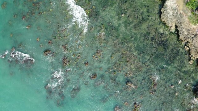 Ocean waves crashing on rocks in plan view. Aquamarine seabed. Anyer Beach in the Indian Ocean. Wallpaper concept. Relaxing nature.