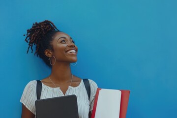 Obraz premium Beautiful African american woman holding files laughing and looking up on a blue wall
