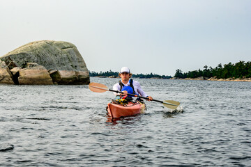 young man in a sea kayak in a wilderness setting  shot in georgian bay ontario late summer room for text