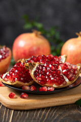 open pomegranates, and pomegranate seeds on wooden table.