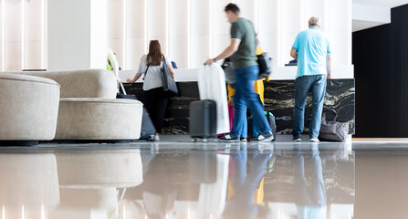 Movement of hotel guests with suitcases in the lobby near the reception