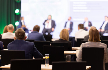 Rear view of the audience at a business conference meeting event listening to the speakers speech