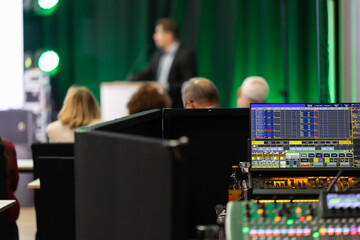 Sound engineer backstage with audio equipment during corporate conference speaker giving a talk