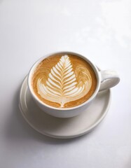A cup of latte with intricate leaf latte art, served in a ceramic mug on a white background