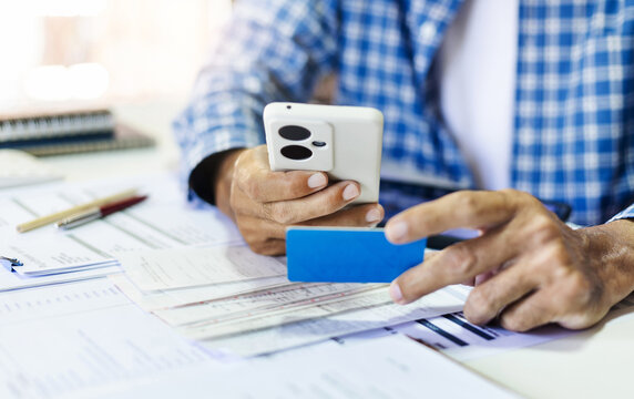 Asian man hands using the smart phone to scan the qr code on blue card to payment online from various bills at the end of the month