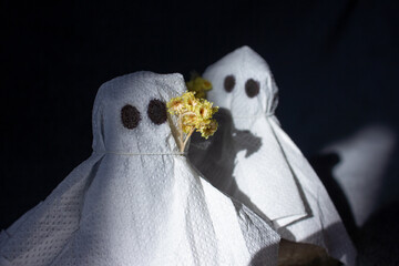 Two cute ghosts made of white napkins with yellow flowers on their heads. We celebrate Halloween. Spooky autumn. Movie style. Spooky season. Cozy Holidays. Handmade