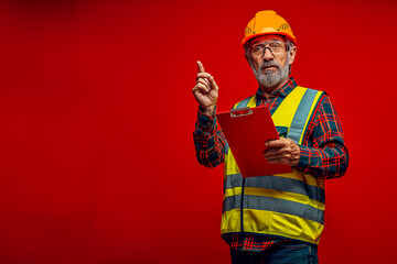 Senior Construction Engineer with Clipboard Pointing Up in Safety Gear