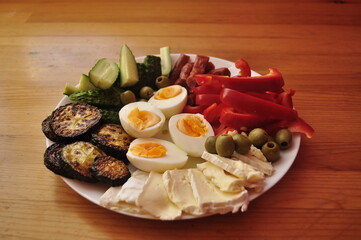 Low-Carb Keto Meal with Eggs, Cheese, Cucumbers, Olives, Sausage, and Red Peppers