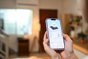 Woman holding a smartphone displaying a home energy monitoring app. Renewable energy concept