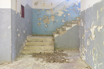 Concrete dilapidated stairwell with peeling painted walls in pastel shades