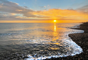 Sunset over a Kent beach with gentle waves lapping on the shore