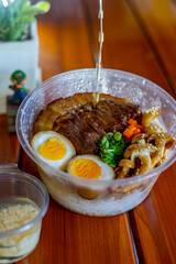 a bowl of rice topped with chashu pork and seasoned boiled egg