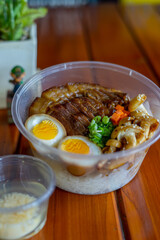a bowl of rice topped with chashu pork and seasoned boiled egg