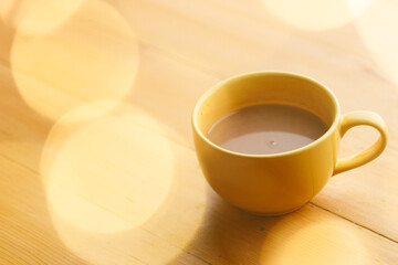 Cup of delicious hot chocolate under with light bokeh on wooden table background. Selective focus.