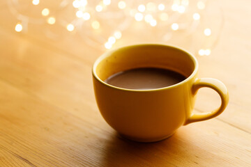 Cup of delicious hot chocolate under with light bokeh on wooden table background. Selective focus.