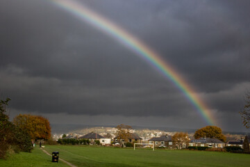 A rainbow's spectrum of colours stands out against a stormy sky over a football field and nearby houses in Cottingley Yorkshire raising thoughts of a pot of gold at its elusive end