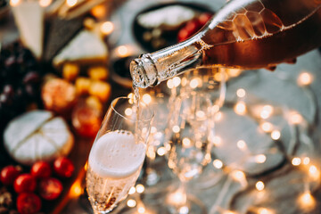 Pouring sparkling wine or champagne served on the table for Christmas or New Year eve celebration.