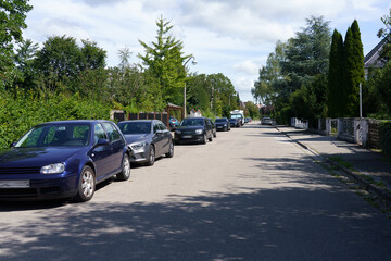 Cars parked on the roadway near private houses.