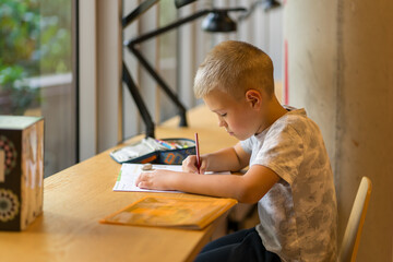 Schoolboy doing homework at a table in the city library