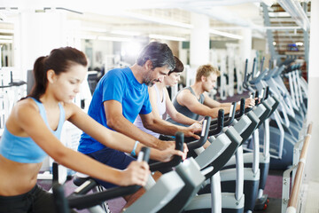 Group, spin class or mature man on cycling machine in training or exercise for wellness or fitness....