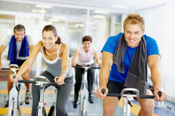 Portrait, spin class or happy people on cycling machine in training or exercise for wellness or fitness. Group, healthy or friends on bicycle for cardio, endurance and workout, body or sports on bike