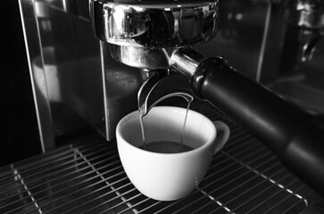 Closeup shot of an espresso maker pouring coffee into a cup inside of a cafe.
