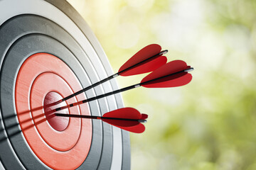 Three red darts hitting the bullseye on a dartboard outdoors. 3D Rendering