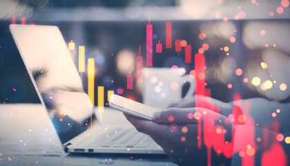 Double exposure image of a person using smartphone with financial graphs overlayed on a blurry background.