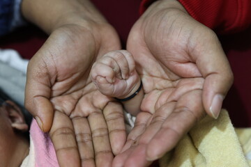 newborn hand welcome with other family members hand at home from different perspective