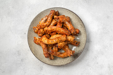 Baked chicken necks in a ceramic plate on a light culinary background top view