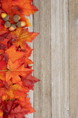 Obraz premium Fall leaves and acorns on weathered wood autumn background