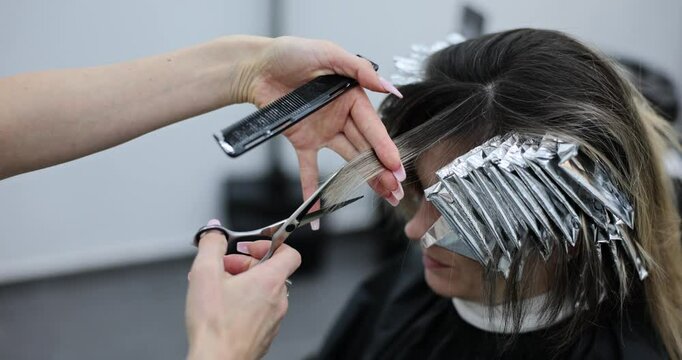 Hairdresser cuts a client bangs in hair salon