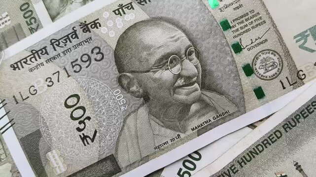 Scattered heap of five hundred Indian rupee bank paper currency notes with Mahatma Gandhi's face. Extreme closeup macro flat lay top view. India inflation, tax, salary, income, EMI, and loan concept.