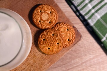Top view of a glass of cold milk and three cookies on a wooden table