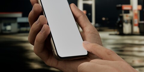Caucasian White male using smartphone with a blank white screen. Nighttime, gasstation, refuel apps mockup. Vertical phone orientation © UnrealHands.com