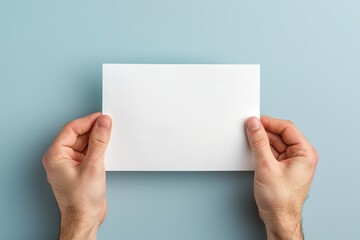 Fototapeta premium Male hands with blank sheet of paper on blue background