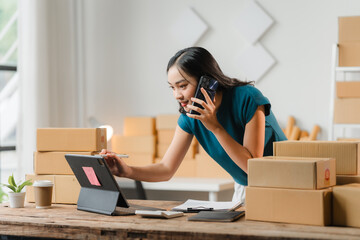 E-commerce Hustle: Young Asian entrepreneur juggling calls and orders amidst a flurry of packages...