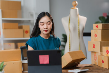 E-commerce Entrepreneur: A young Asian woman meticulously packs orders for her online fashion...