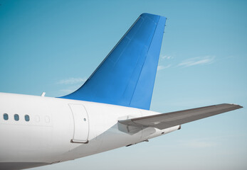 Modern aircraft's tail assembly on a sunny day. Empennage of white airplane with blue vertical stabilizer, clear sky in the background.  © andrbk