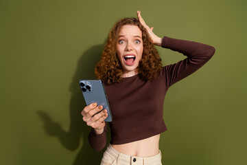 Photo of shocked impressed girl wear brown shirt getting emails modern gadget empty space isolated khaki color background