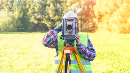 Woman engineer surveyor topographer performs measurements when drawing up a land survey plan