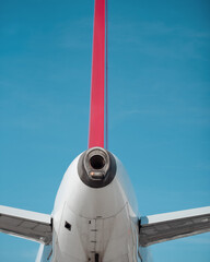 Vertical stabiliser and auxiliary power unit (APU) of white aircraft against clear blue sky. White...