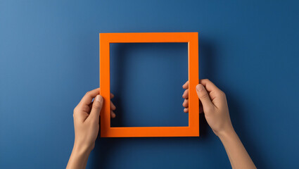 A rectangular orange photo frame hangs on a bare concrete wall.