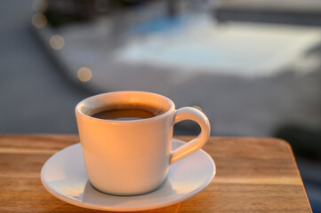 Obraz premium a cup of black Turkish coffee on the balcony with the pool as a background