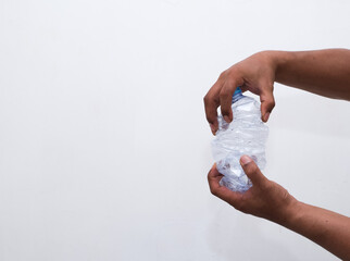 The concept of stop plastic, recycling. Female hand holding a crumpled plastic bottle on a white...