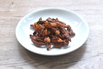 fried crispy salty fermenting beef meat with pandan and herb on plate 