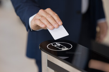Hand of business man holding electronic keycard at sensor control keypad, using security system, applying identity badge for gate unlock at office entrance, using business security system. Close up