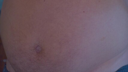 A man measures his fat belly with a measuring tape. Close-up.