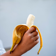 Closeup view of hand of a child holding a half eaten banana